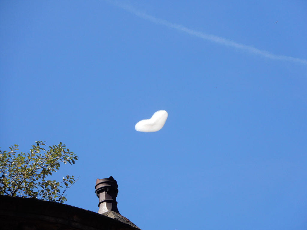Heart -shaped balloon flies in clear blue skies above the Manchester Pride parade