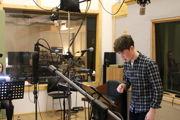 Elliot Gray, University of Salford alumnus conducts the university’s brass band during recording of the song at 80 Hertz Studios