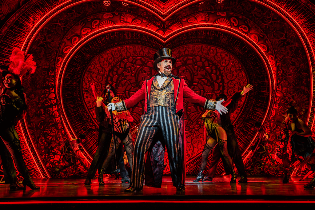 Cameron Blakely as Harold Zidler and the original world tour company of Moulin Rouge! The Musical Photo credit – Johan Persson