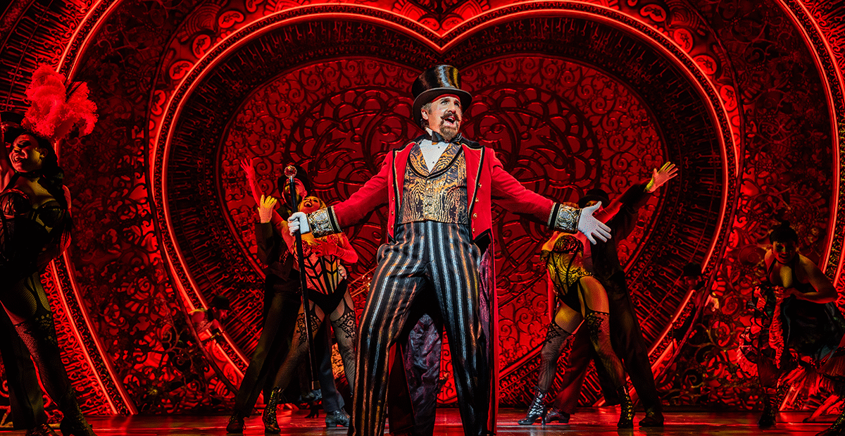 Cameron Blakely as Harold Zidler and the original world tour company of Moulin Rouge! The Musical Photo credit – Johan Persson