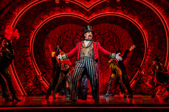 Cameron Blakely as Harold Zidler and the original world tour company of Moulin Rouge! The Musical Photo credit – Johan Persson
